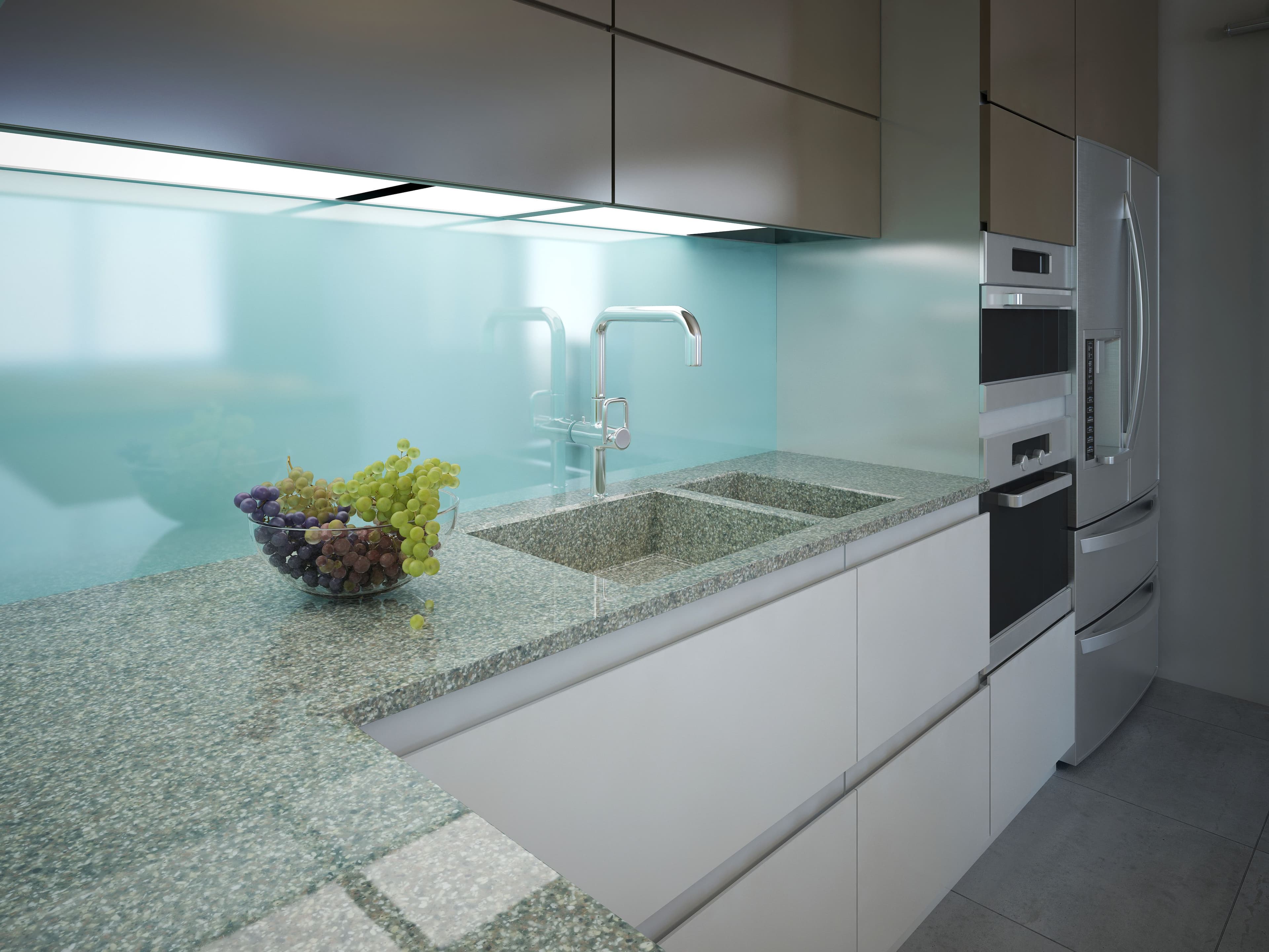 Acid etched light blue glass splashback mounted flush behind a double granite sink with chrome tapware in a modern contemporary kitchen.