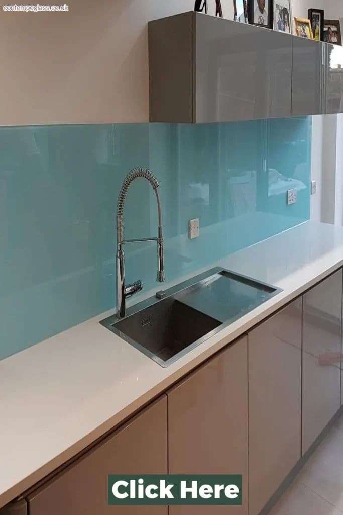 Pale aqua blue glass splashback mounted flush on the wall behind a stainless steel undermount sink with a chrome spring-neck tap in a modern white kitchen.