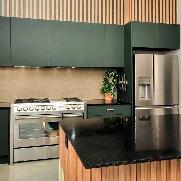 A textured stone or laminate splashback panel mounted behind a professional gas range cooktop in a modern kitchen with dark green cabinetry and black stone benchtops.
